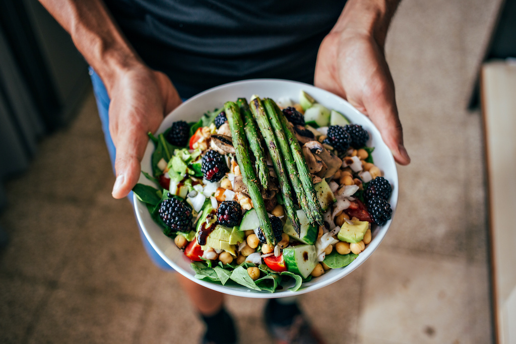 Man hands holding big deep plate full of healthy paleo vegetarian salad made from fresh organic biological ingridients, vegetables and fruits, berries and other nutritional things