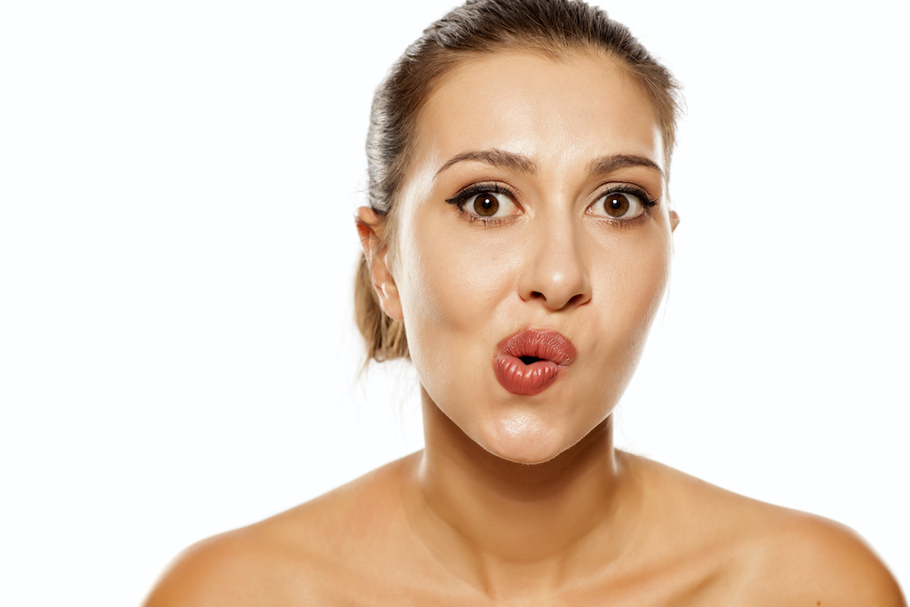 A young woman stretches out her mouth and cheeks