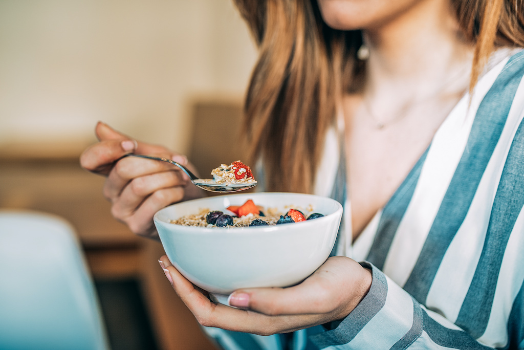 woman eating oat and fruits bowl for breakfast
