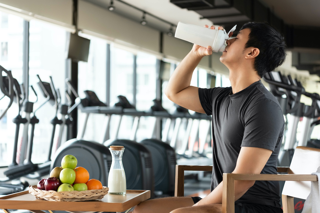 Handsome man drinking protein shake milk and many kind of fruits for nourishing body daily. People lifestyles and Nutrition food concept. Nutrition of sport man theme.