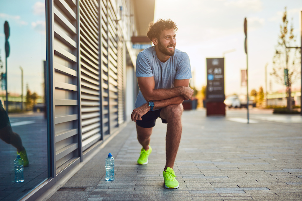 Young man exercising / stretching in urban area.