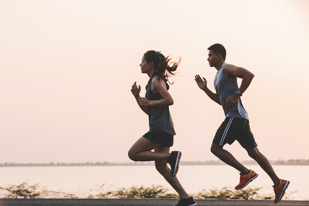 young couple runner running on running road in city park