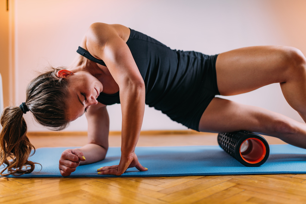 Sporty Woman Self Massaging Legs with Foam Roller at Home